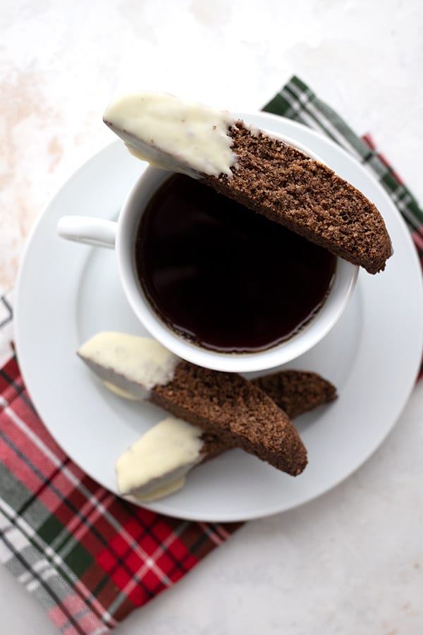 Top down image of keto white chocolate gingerbread biscotti sitting on the edge of a cup of coffee