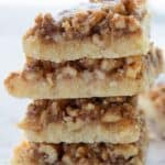 Titled image of a stack of keto baklava bars on a rustic table with crumbs around the bottom.