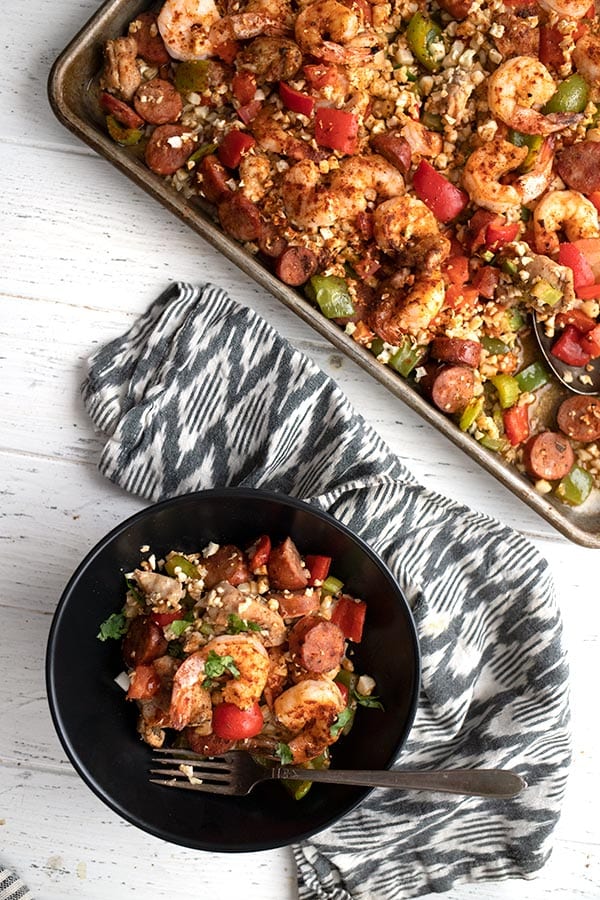 Top down image of keto sheet pan jambalaya with some of the meal in a black bowl.