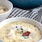 Titled image of a white bowl filled with keto seafood chowder on a white wooden table.