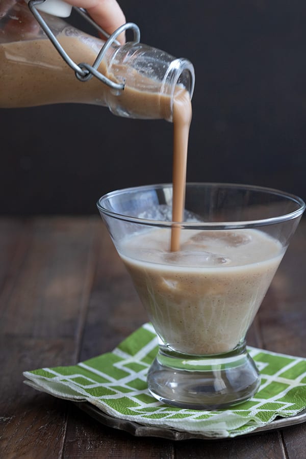 A bottle pouring keto Irish Cream into a glass full of ice.