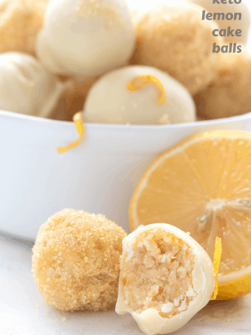 Titled image of keto lemon cake balls in a bowl, with two in front. One has a bite taken out of it.