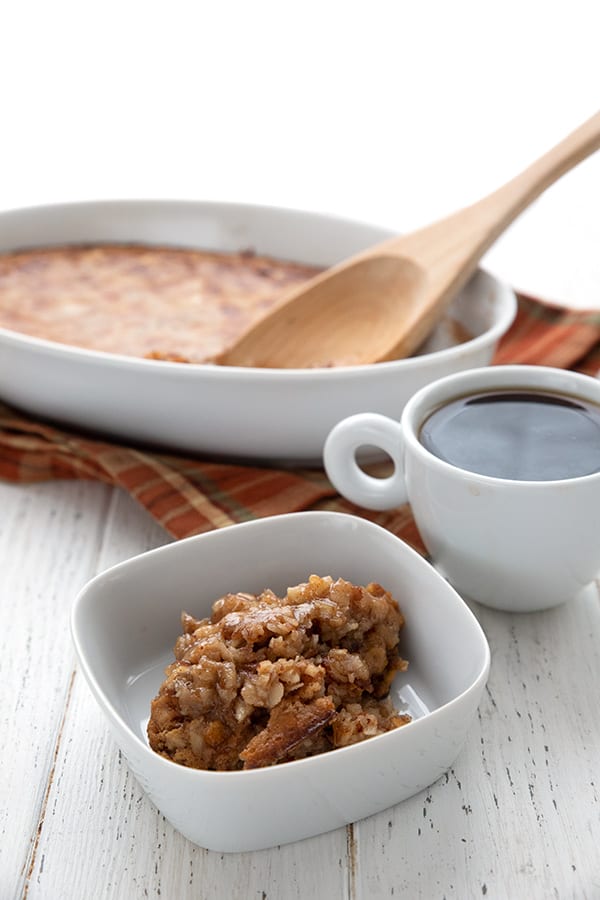 A dish of keto baked oatmeal with a cup of coffee on a white table.
