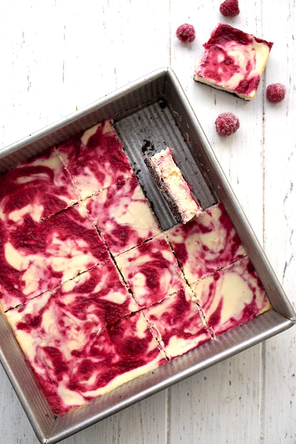 Top down image of a pan of keto raspberry swirl cheesecake bars on a white table.