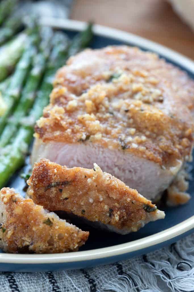 Close up shot of parmesan crusted pork chops sliced to show the juicy interior.