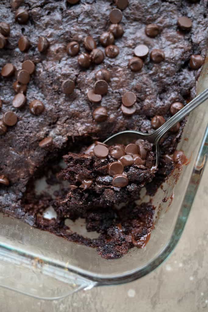 Top down image of keto chocolate dump cake in a glass pan, with a scoopful take out of it.