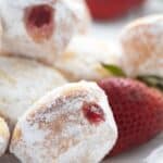 Titled Pinterest image of keto jelly donut bites on a white plate with strawberries.