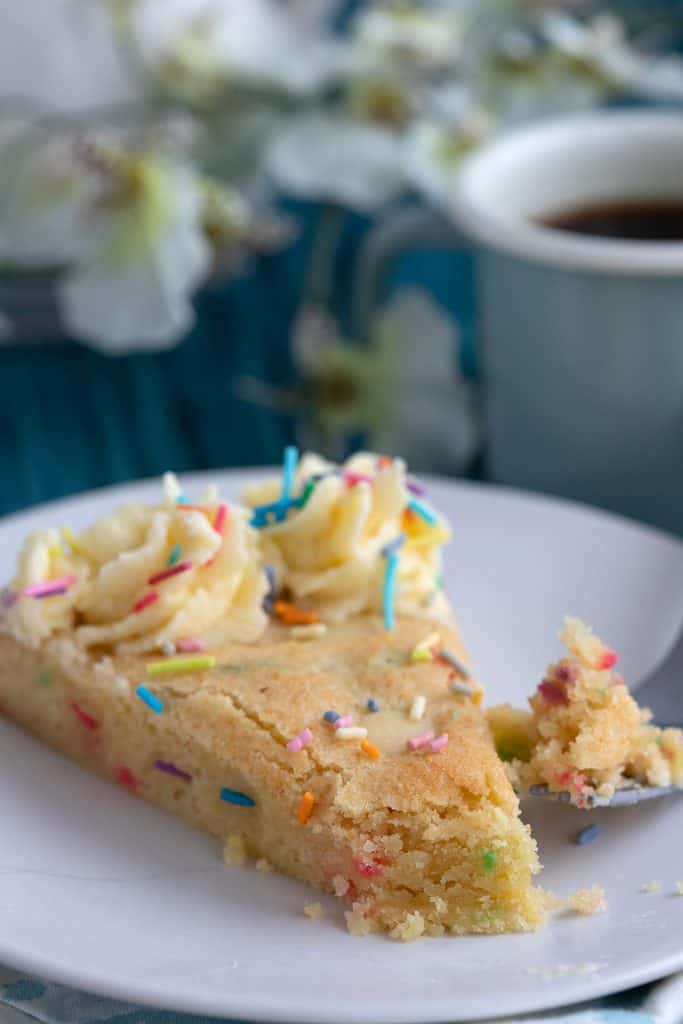 Close up shot of sugar cookie cake with a forkful taken out of it.