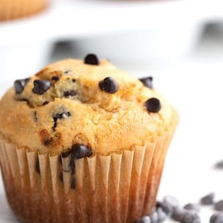 Close up shot of a bakery style keto muffin with chocolate chips all around it.