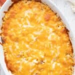 Top down image of ham and cauliflower casserole in a white oval baking dish.