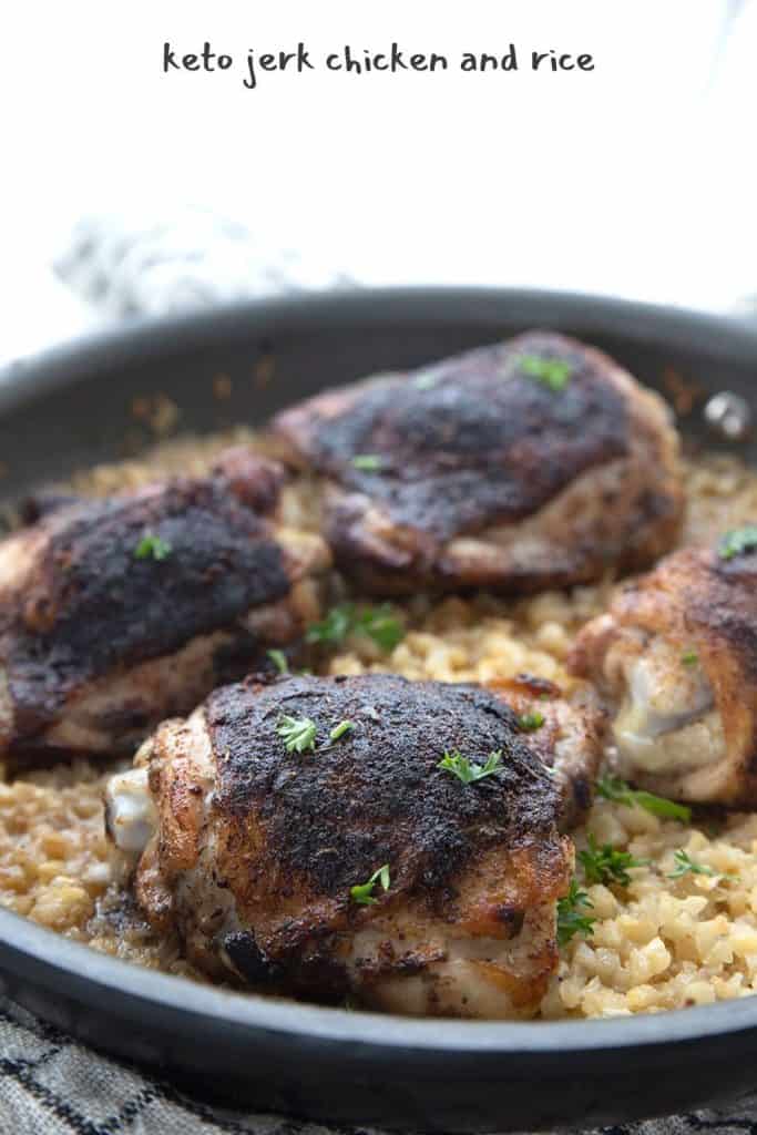 Close up shot of keto jerk chicken and cauliflower rice in a skillet, with parsley sprinkled over top.