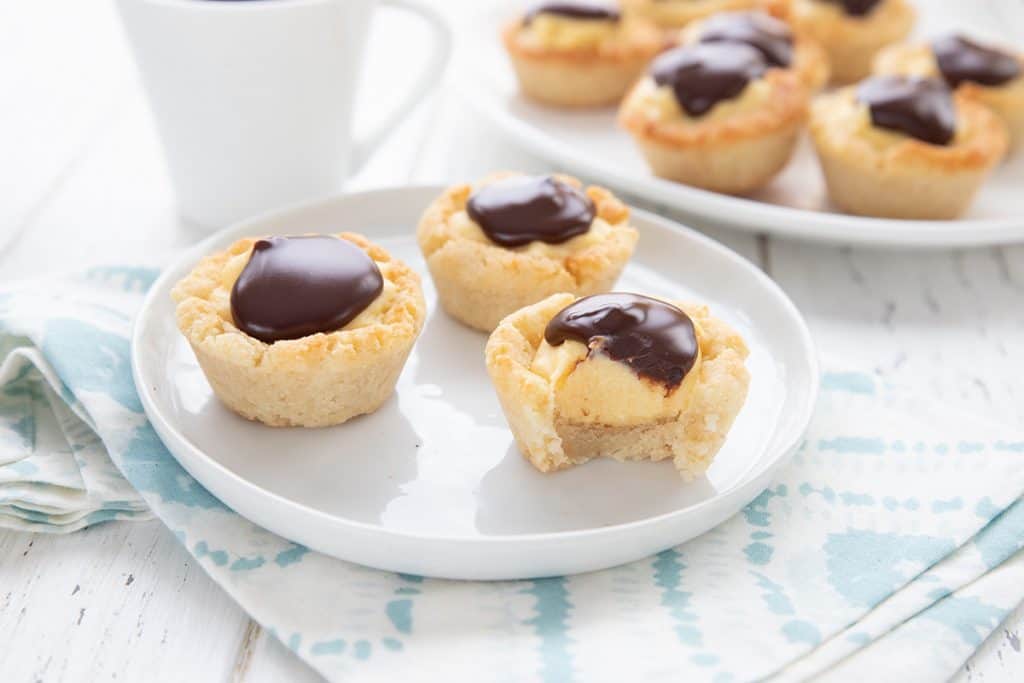 Three keto Boston Cream Cookie Cups on a white plate with a bite taken out of one.