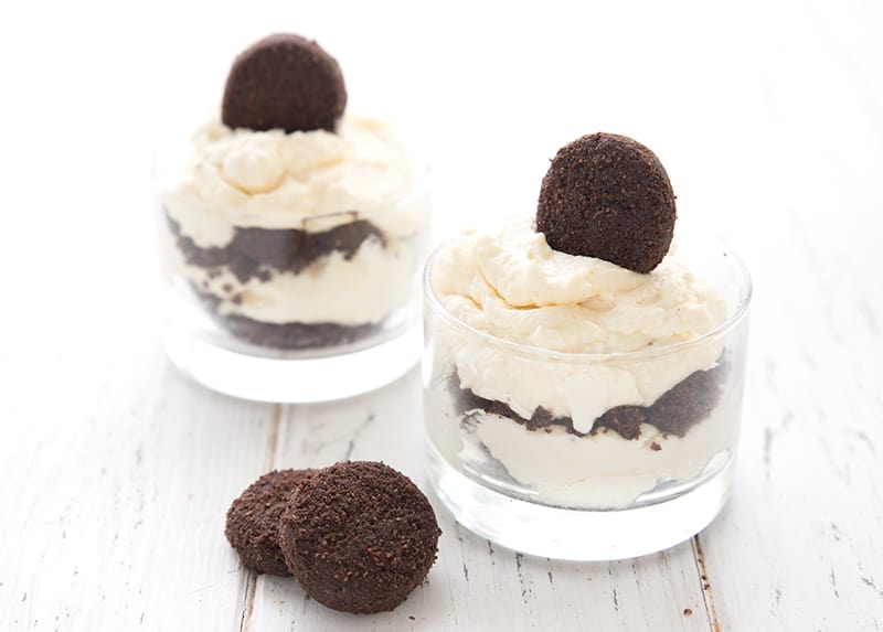 Two keto brownie parfaits on a white table with some sugar free brownie bites.