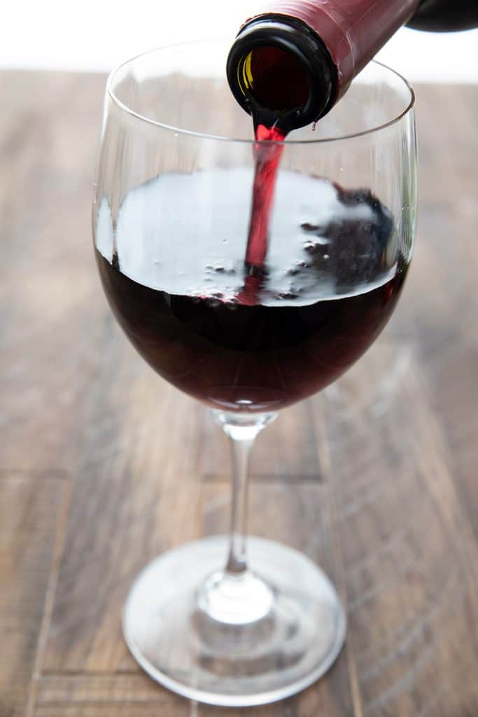 Close up shot of red wine being poured into a glass.