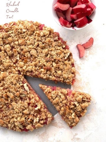 Titled image: top down photo of keto rhubarb tart on a white table, with a slice removed.