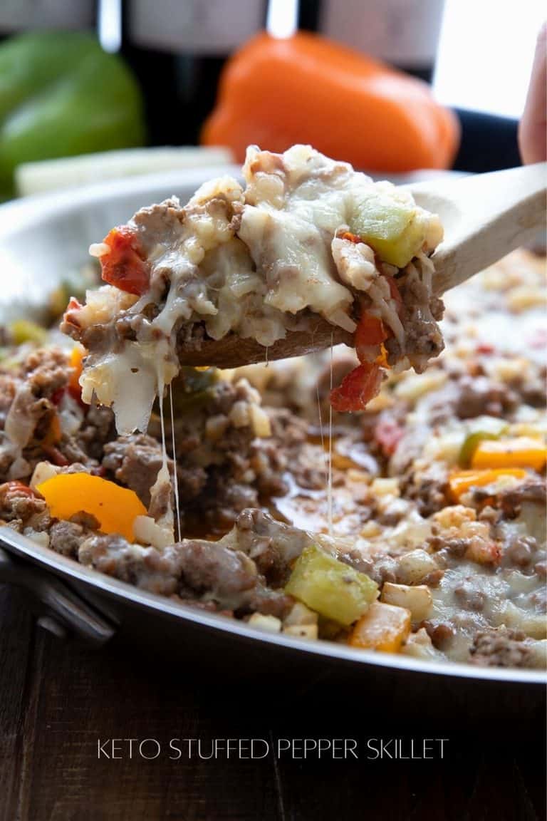 Titled image of a wooden spoon scooping cheesy unstuffed peppers out of a skillet.