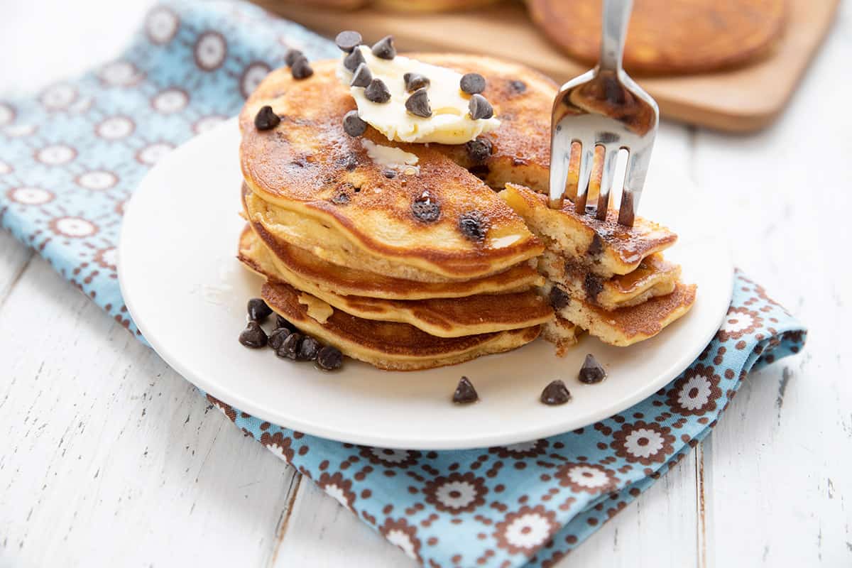 A stack of banana chocolate chip pancakes with a forkful being taken out.