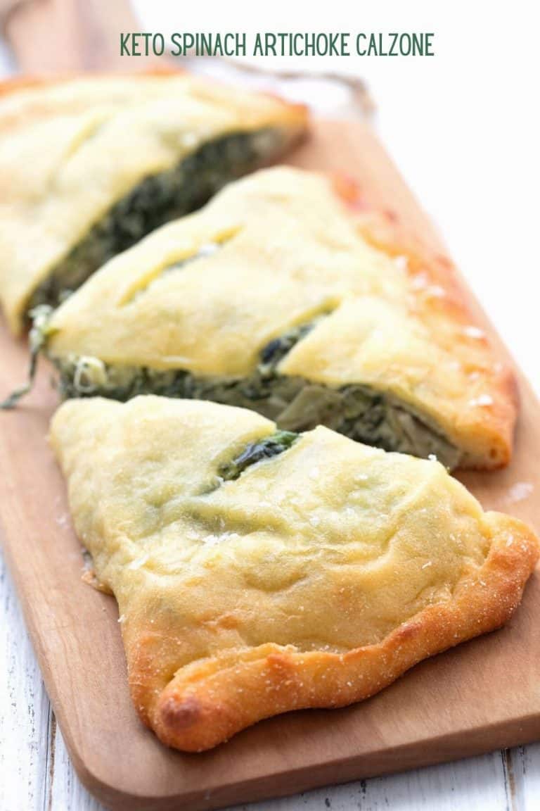 Titled image of a keto spinach artichoke calzone on a cutting board, cut into three pieces.