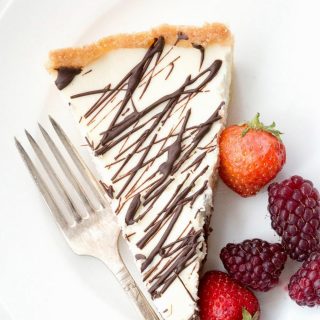 Top down image of a slice of keto cannoli tart with berries on the side, on a white plate.