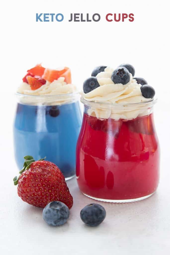 Titled image for keto sugar free jello in glass jars, one blue and one red, topped with whipped cream and berries.