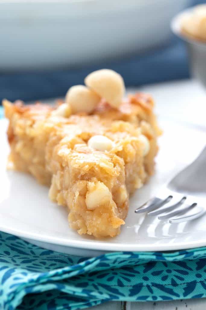 Close up shot of sugar free macadamia nut pie in a white plate over a blue patterned napkin.