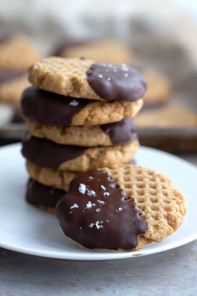 A white plate with a stack of chocolate dipped peanut butter cookies.