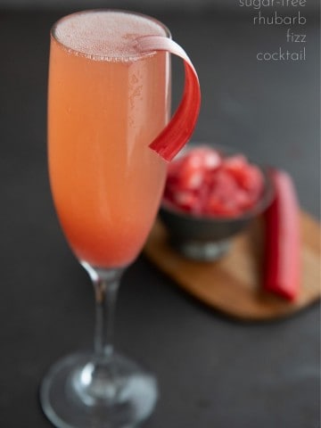 Titled image of a sugar free rhubarb cocktail in a champagne flute with a strip of peeled rhubarb as garnish.
