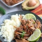 Keto Carnitas and cauliflower rice on a black plate over a colorful striped napkin.