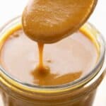 Titled image of a wooden spoon digging into a jar of mustard-based sugar-free BBQ Sauce.