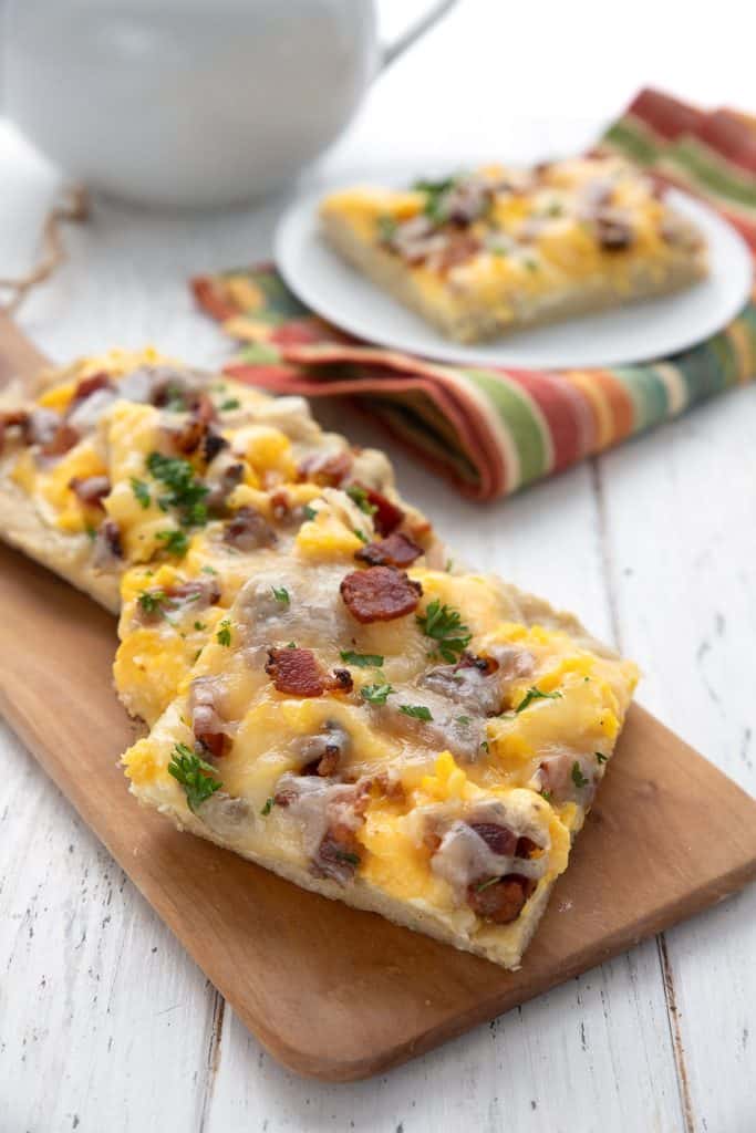Three slices of keto breakfast pizza on a wooden cutting board.