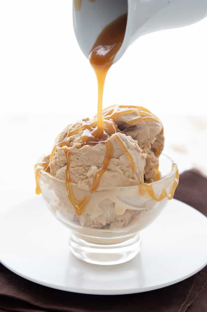 Keto caramel sauce being drizzled over a bowl of keto salted caramel ice cream.