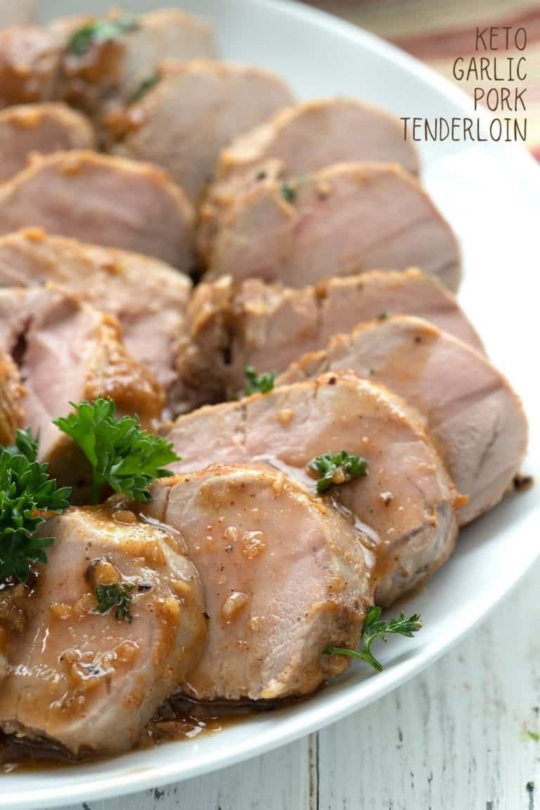 Titled image of slices of pork tenderloin on a white plate, drizzled with garlicky sauce.