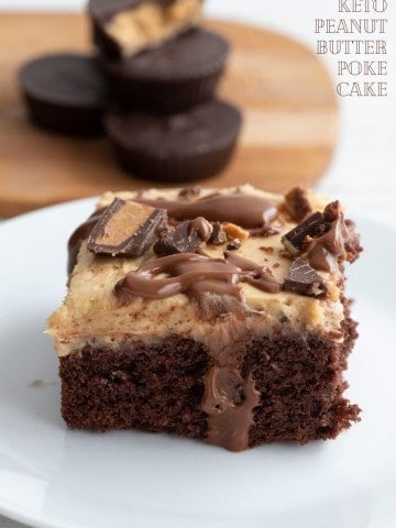 Titled image of keto chocolate peanut butter poke cake on a white plate, with keto peanut butter cups in the background.