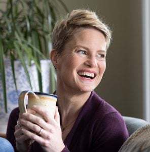 Photo of Carolyn Ketchum drinking coffee and laughing.