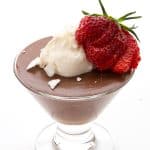 Keto chocolate pudding in a glass dessert cup with whipped cream and a strawberry on top.