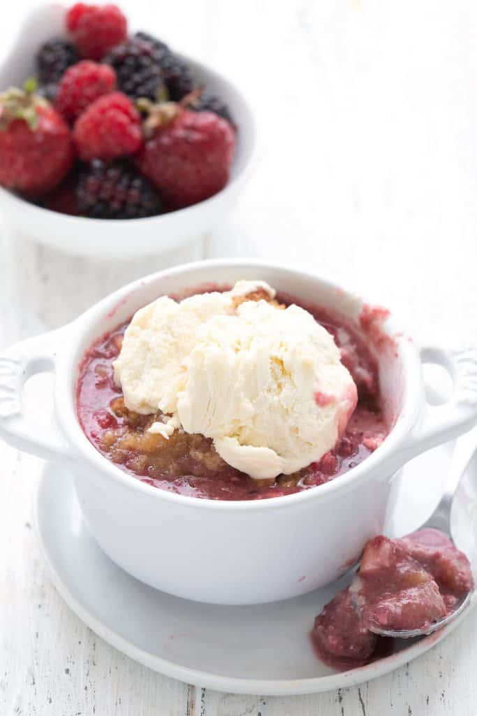 A serving of keto berry cobbler in a ramekin with ice cream on top.