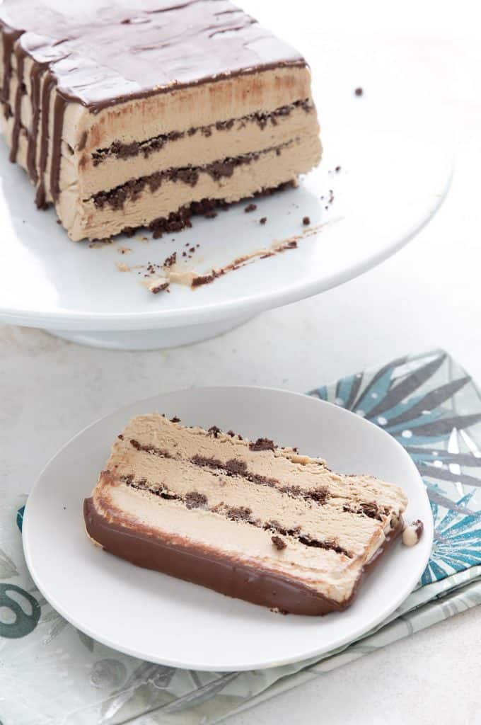 Easy coffee ice cream cake on a white cake platter, with a slice on a white plate in front.