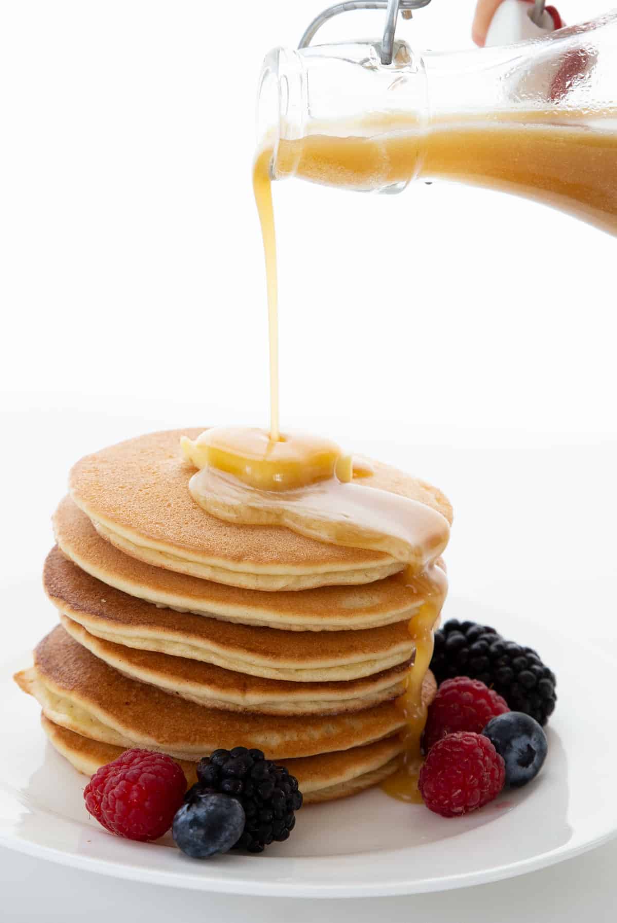 Sugar free keto syrup being poured over a stack of keto pancakes.