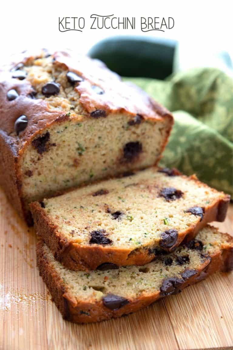 Close up shot of a loaf of keto zucchini bread on a wooden cutting board with two slices front.