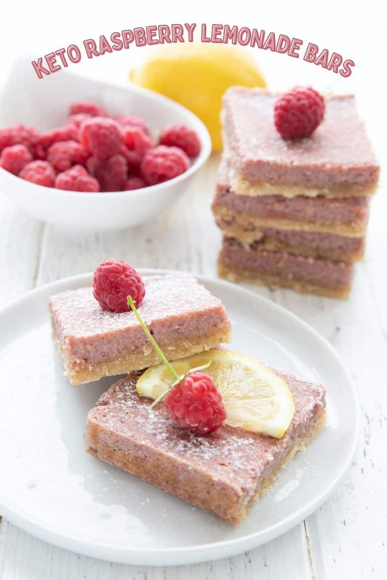 Titled image of keto raspberry lemonade bars on a white plate with a bowl of raspberries and a lemon in the background.