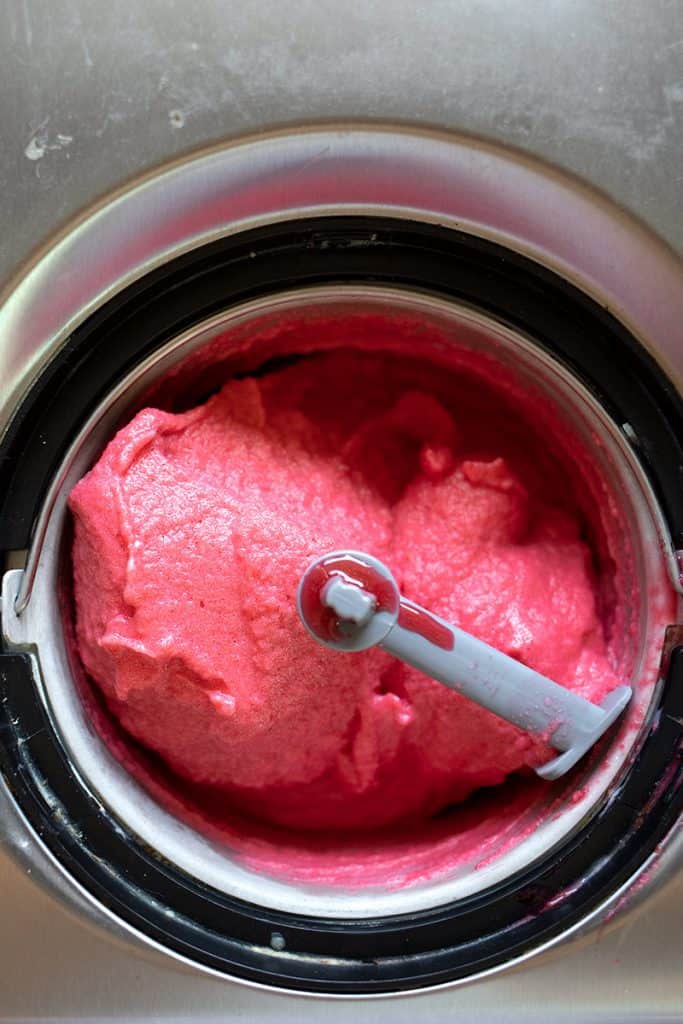 Top down image of keto raspberry sorbet in an ice cream maker.
