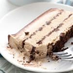 A slice of keto coffee ice cream cake on a white plate over a blue patterned napkin.