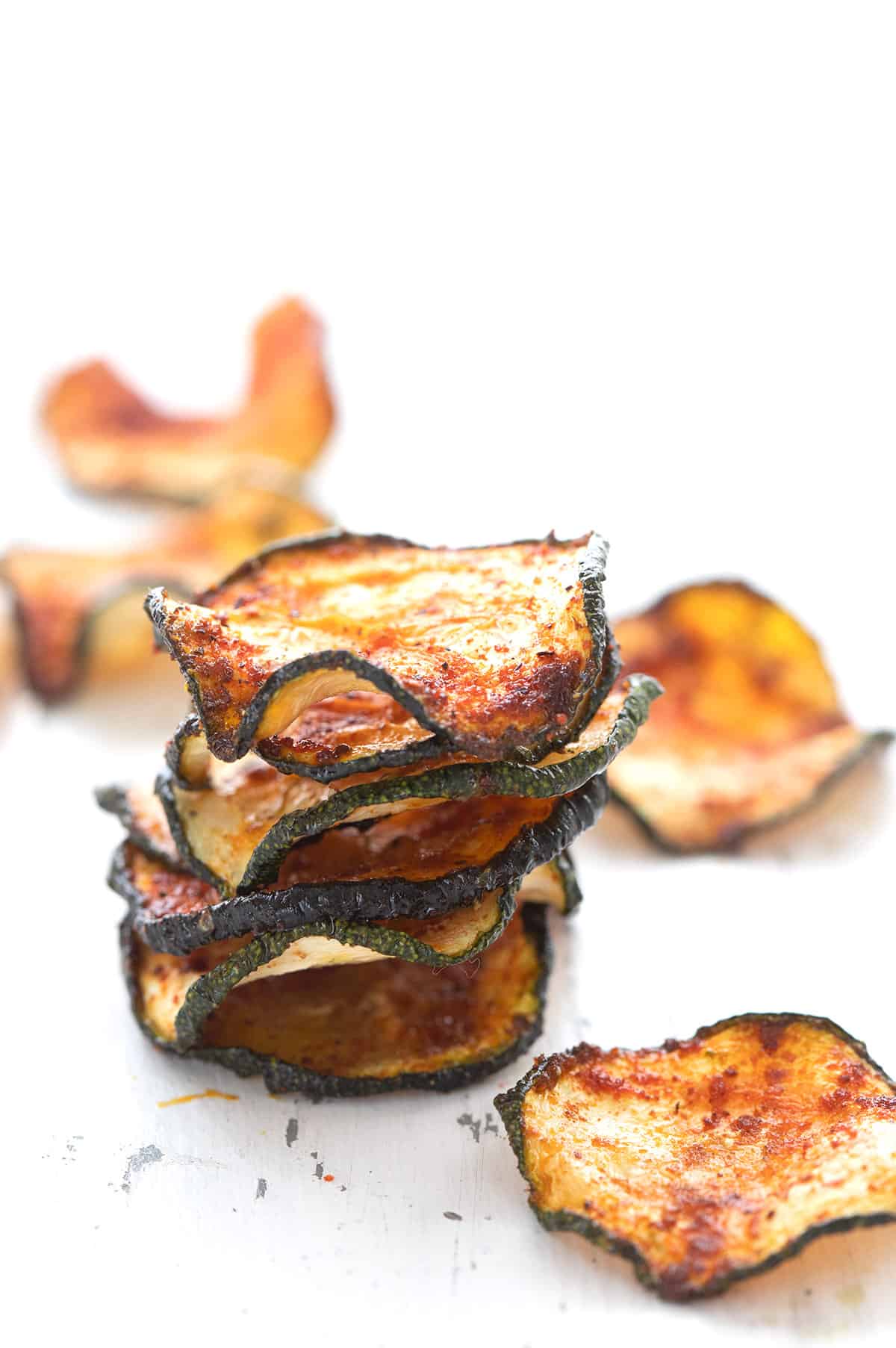 A stack of baked zucchini chips on a white table.
