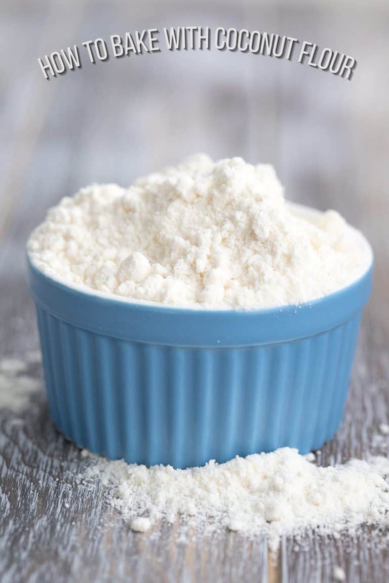 A blue ramekin full of coconut flour on a wooden table.