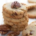 Close up shot of a stack of low carb butter pecan cookies with pecans scattered around.
