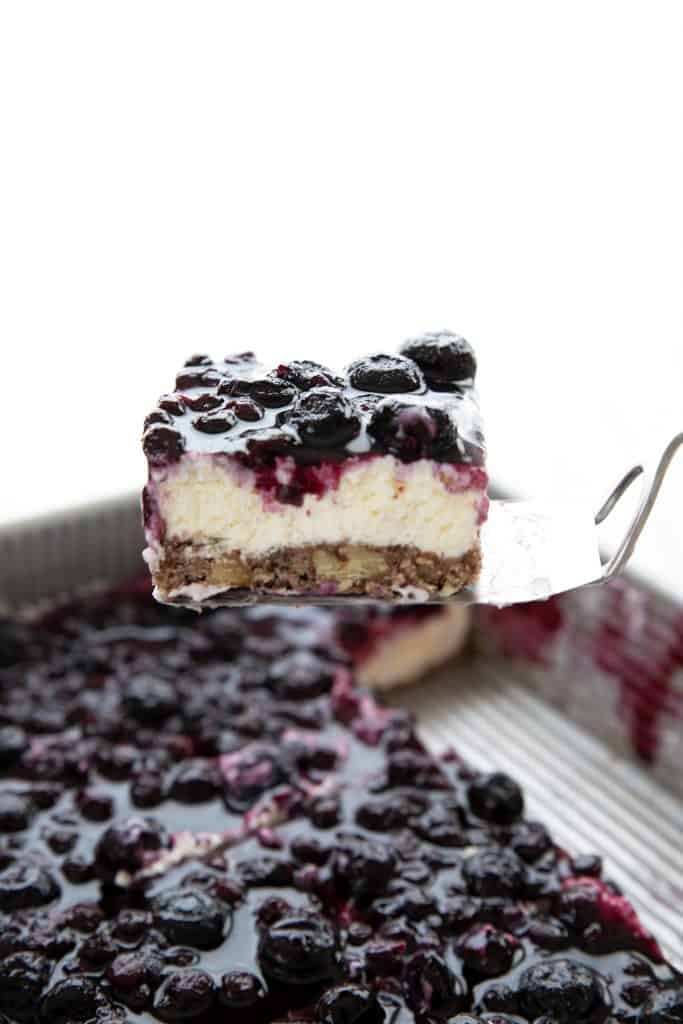 Lifting a slice of keto blueberry jamboree dessert out of the pan.