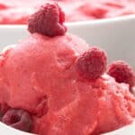Titled Pinterst image of keto raspberry sorbet in a white bowl with raspberries on top.