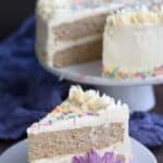 Titled Pinterest image of Keto Birthday Cake on a white plate with a purple flower.