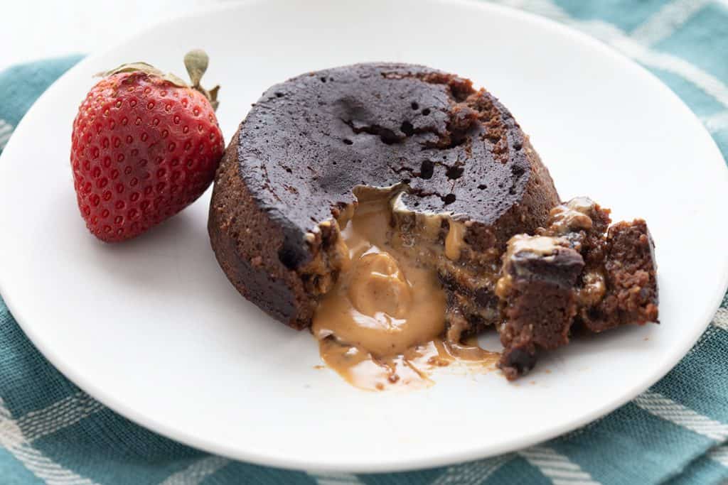 Close up shot of keto lava cake on a plate, broken open to show the peanut butter oozing out.