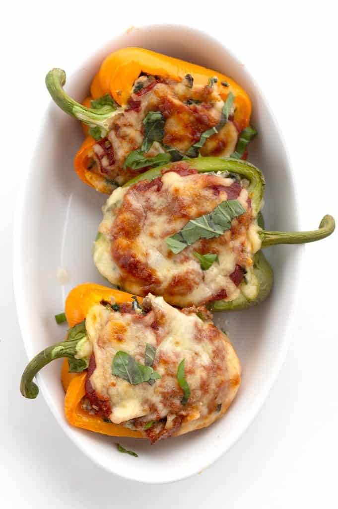 Top down image of 3 keto stuffed peppers in an oval baking dish.